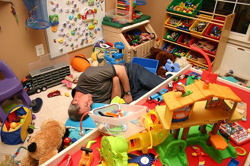 Мужчина спит среди разбросанных игрушек